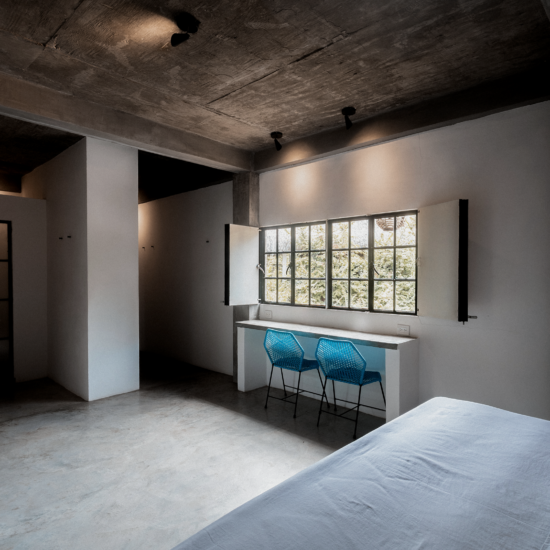 King Bedroom interior at Soirée with a king-size bed, desk and windows overlooking tropical greenery